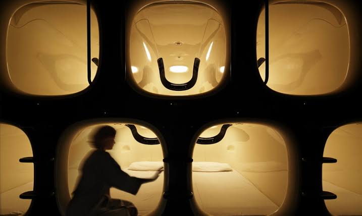 Narrow corridor of a capsule house with stacked sleeping berths on both sides